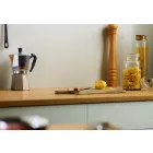 Pebble Satin Cladding installed above a wooden kitchen worktop. The surface is holding a chopping board, glass storage jars and a coffee percolator.