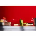 Ruby Gloss Cladding installed above a stainless steel kitchen worktop. The surface is holding a chopping board, pans, utensils, and various colourful peppers.