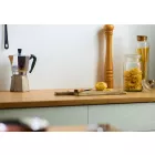 White Satin Cladding installed above a wooden kitchen worktop. The surface is holding a chopping board, glass storage jars and a coffee percolator.