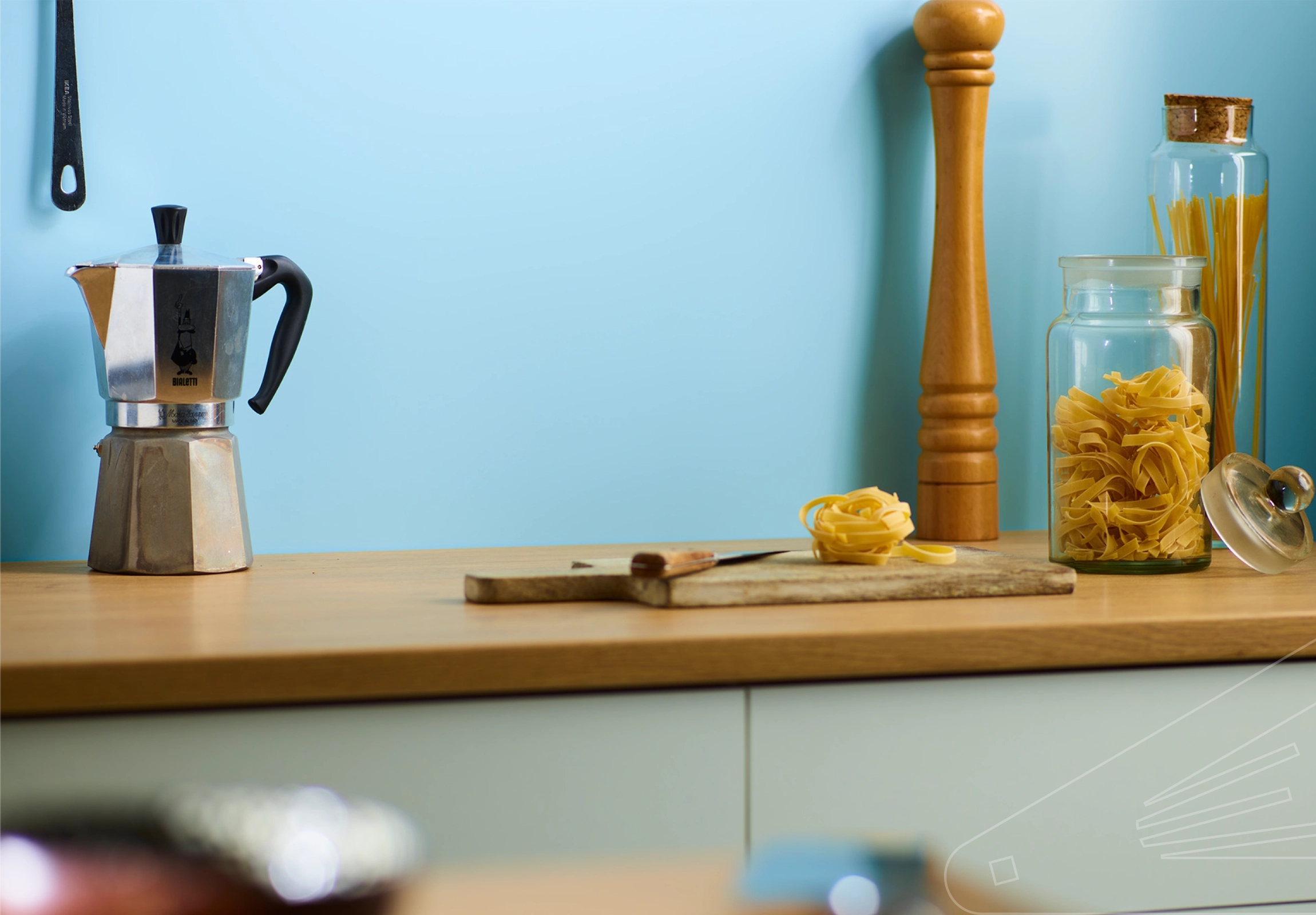 Sky Satin Cladding installed in kitchen above wooden work surface with Kitchen accoutrements.