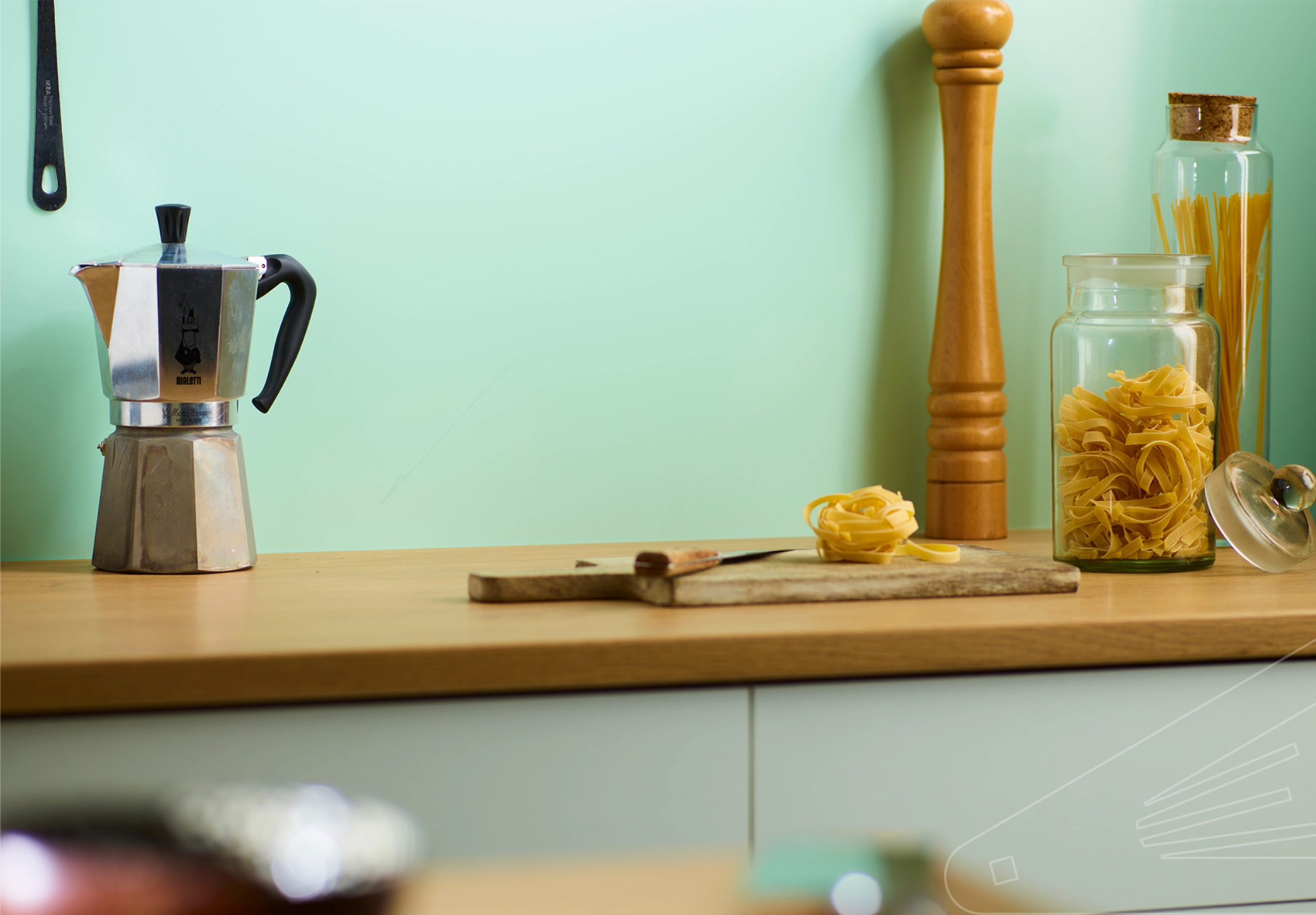 Willow - Satin Cladding installed in above a wood coloured Kitchen Worktop with Glass Jar's and Pepper Grinder.