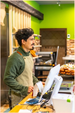 Young male in cafe shop behind till with lime green cladding on shop walls