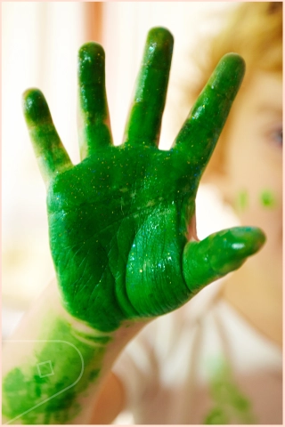Children's hand with wet green paint
