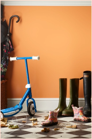 Entryway with an Apricot Satin wall, children’s scooter, rain boots, and small shoes on a tiled floor, with leaves scattered near the door.