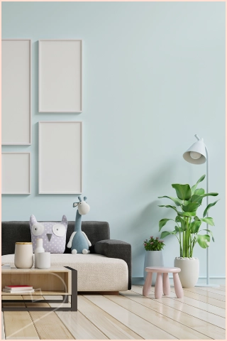 Bright living room with Sky Satin cladding installed behind a sofa, decorative pillows, plants, framed wall art and light wood flooring in soft neutral colors.