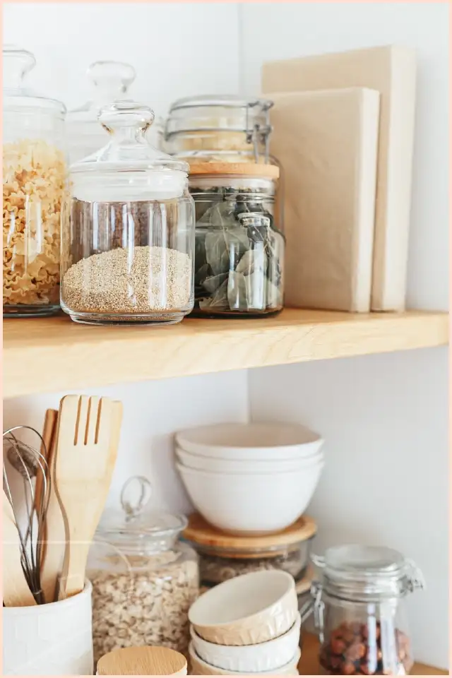 Small pantry with satin white cladding and organised shelving with glass storage jars.